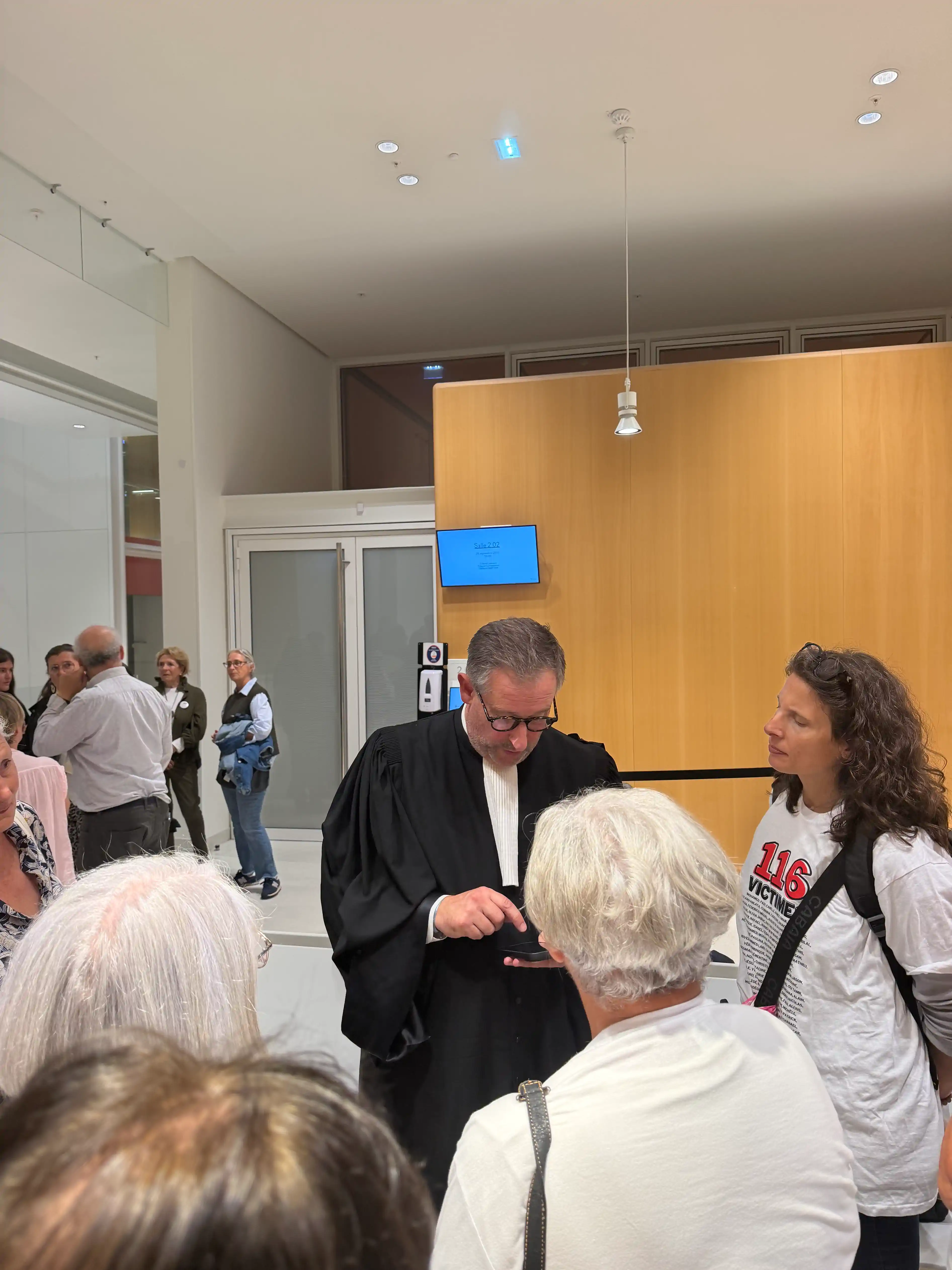 Abogado con toga rodeado de asistentes en el pasillo · Sentencia Swiftair, vuelo Air Algérie AH5017, 28 de septiembre de 2026. Abogado con toga rodeado de asistentes en el pasillo